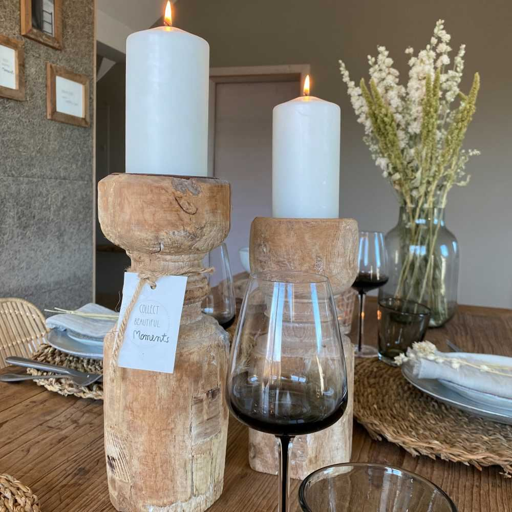 Festlich gedeckter Holztisch mit zwei großen Kerzenständern aus Holz, Rotweingläsern, Seegras-Tischsets und Trockenblumen