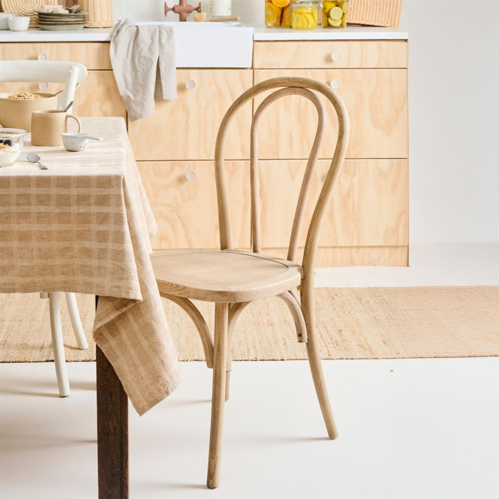 Stuhl Wien aus gebogener Ulme an einem Tisch mit karierter Tischdecke, im Hintergrund eine helle Holzküche